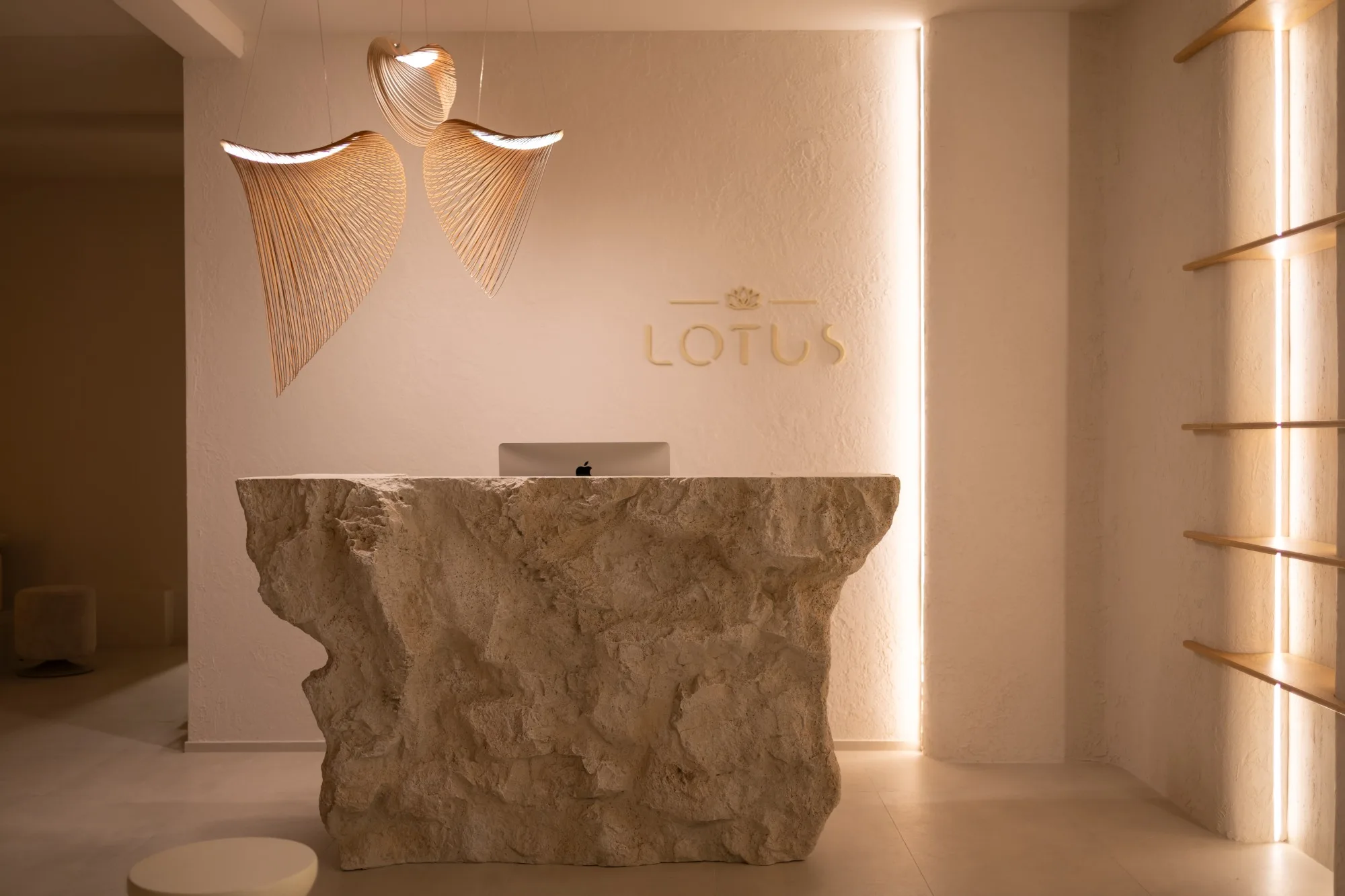 Kameni pult recepcije ispod logotipa LOTUS i osvijetljene police